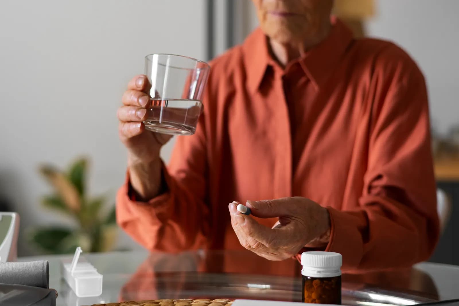 mature woman taking vitamin supplements pills with glass of water, healthy lifestyle over 50
